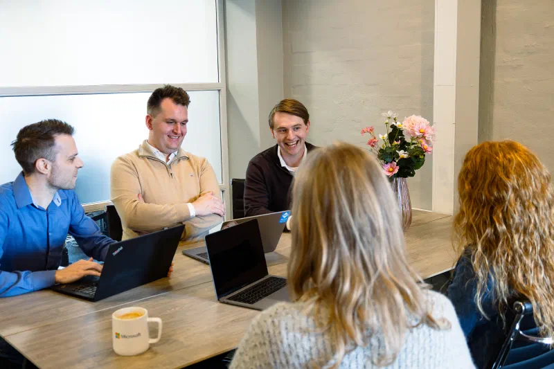Picture of people sat around a table, discussing a project